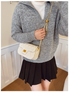 Detailed view of quilted white chain bag with gold hardware worn by a model