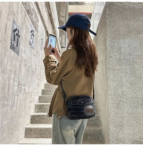 Street style view of a vintage washed denim crossbody bag with brown leather brand patch