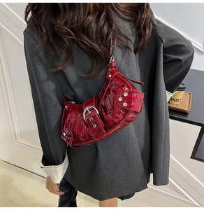 Detail of dark red faux crocodile leather shoulder bag with silver studs and belt buckles