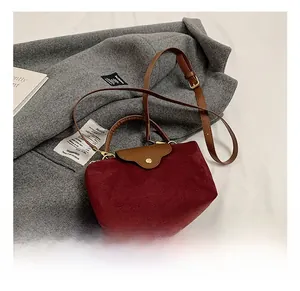 Detail of burgundy velvet mini handbag showing wave-edge flap and golden snap button