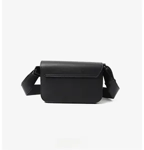Detail view of the back pocket and textured cross-grain leather of this black crossbody bag