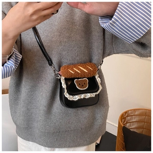 Detail of lace-trimmed handbag with teddy bear patch and plush baguette handle