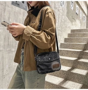 Detail of adjustable denim strap and brown leather patch on a retro washed crossbody bag