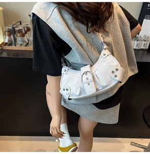 Close-up of white crocodile pattern shoulder bag with silver buckle and rivets