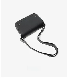 Detail of black crossbody bag featuring textured faux leather and silver metal rivets