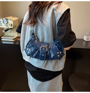 Close-up of blue crocodile pattern patent leather shoulder bag with silver rivet details