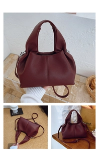 Detail of burgundy lychee grain leather handbag with pleated design and silver hardware