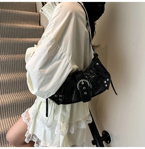 Close-up of black crocodile embossed patent leather shoulder bag with silver rivet details
