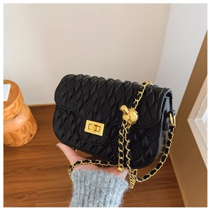 Detailed macro view of black Matelassé pleated texture and gold square lock on bag