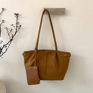 Detail of caramel brown tote bag with matching pouch and stylish belt buckle accents