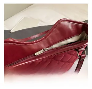 Vue détaillée du sac matelassé rouge avec fermeture éclair argentée et doublure chevron