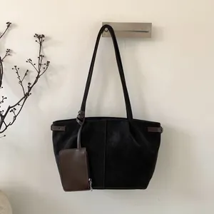 Detail of matte black suede tote bag with brown handles and matching coin purse charm