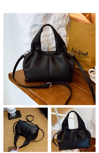 Close-up of black lychee texture dumpling bag with top handles and adjustable strap