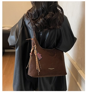 Detailansicht der braunen Wildledertasche mit geflochtenem Anhänger und Leoparden-Bär