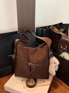 Vintage dark brown tote bag with pleated texture and plush bunny charm on white stand