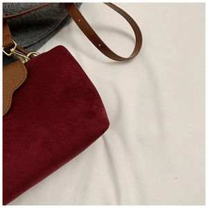 Detail of burgundy suede and brown lychee leather bag with gold hardware buckle