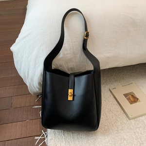 Close-up of black PU leather bucket bag with vintage gold clasp on a cozy floor setting
