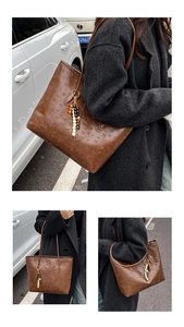 Detailed close-up of brown tote bag featuring embossed patterns and wooden bead tassel