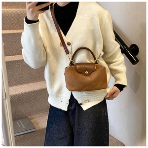 Brown leather handbag shown on stairs with a detachable shoulder strap and top handle