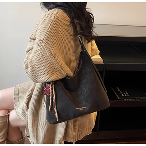 Detail der dunkelbraunen Leder-Shopper mit geflochtenem Anhänger und Leoparden-Charm