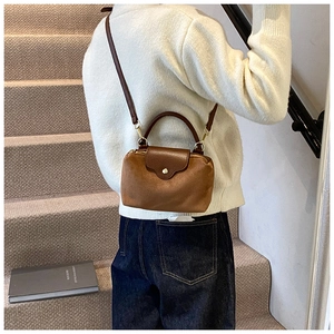 Brown dumpling cross-body bag shown on model in a cozy interior home setting