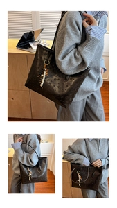 Detail of black tote bag with embossed texture, featuring a decorative beaded tassel charm