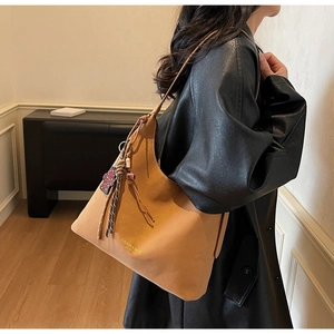 Nahaufnahme der braunen Ledertasche mit Blumenanhänger und goldener Aufschrift