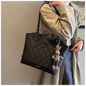 Sac fourre-tout matelassé avec pendentif lapin porté sur un trench-coat