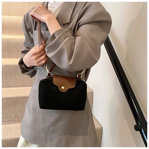 Detail of a two-tone nylon handbag with brown leather flap and golden metal buckle