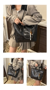 Close-up of black embossed tote bag with beaded pendant and thin shoulder straps