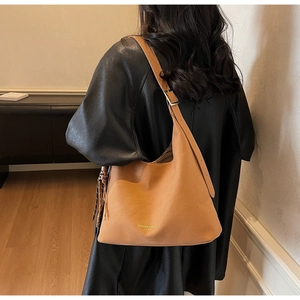 Detailansicht der karamellfarbenen Eimertasche mit Goldschnalle und Quasten-Akzent