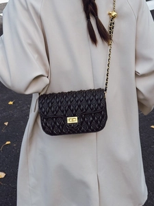 Minimalist black quilted crossbody bag with gold metal chain and turn-lock closure