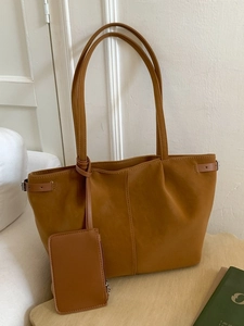 Minimalist camel leather tote bag with vertical stitching and matching small charm pouch