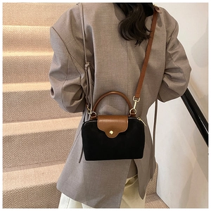 Minimalist black and brown crossbody bag shown on a model in a stylish beige setting