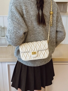 Elegant white quilted crossbody bag with gold twist lock and chain strap on marble surface