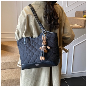 Détail d'un sac cabas noir matelassé avec une peluche de lapin et texture en nylon