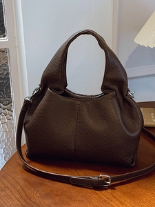 Brown lychee grain leather dumpling bag with adjustable shoulder strap in warm setting