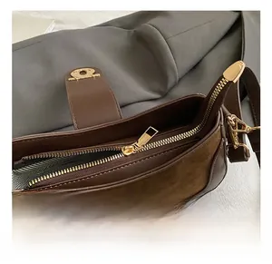 Detail of brown suede leather handbag showing golden zipper and herringbone lining