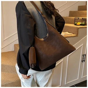 Detail of dark brown tote bag showing adjustable strap and small zipper pouch