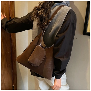 Detail of vintage brown tote bag with white stitching and hanging zipper pouch accessory
