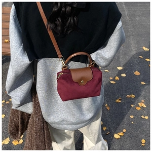 Detail of burgundy nylon mini crossbody bag with leather flap and gold hardware