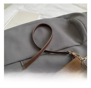 Detail showing the brown frosted leather texture and golden metal buckle of the bag