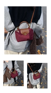Detail of burgundy nylon mini crossbody bag with brown leather handles and gold snap button