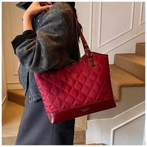 Sac cabas matelassé rouge porté à l'épaule par un mannequin en manteau de laine