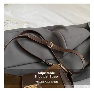 Detail of adjustable leather shoulder strap with gold buckle on dark brown suede handbag