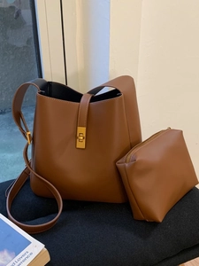 Brown leather bucket bag set with gold twist lock and matching pouch on dark cushion
