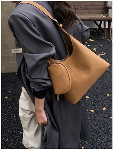 Close-up of caramel brown leather tote bag with unique half-moon zipper pouch detail