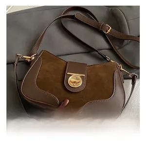 Detail of a brown suede and leather crossbody bag with a gold round twist lock