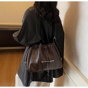 Detail of dark brown quilted leather bucket bag featuring a drawstring closure