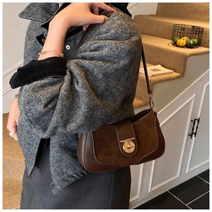 Detail view of brown leather and suede shoulder bag with gold metal twist lock buckle